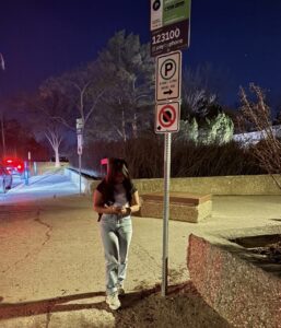 Mariel Mallari standing beside a Pay by Phone sign while using the Pay by Phone app.