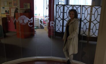 A photo of Jill Arnott in front of the Women's Centre window.